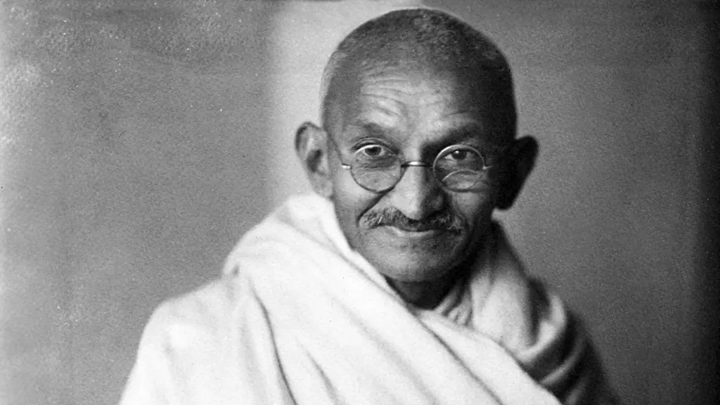 Ritratto in bianco e nero di Mahatma Gandhi sorridente, avvolto in uno scialle bianco