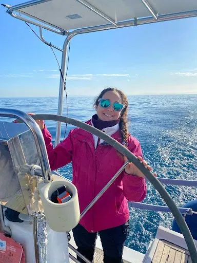 Una partecipante al timone della barca a vela, con il mare aperto alle spalle
