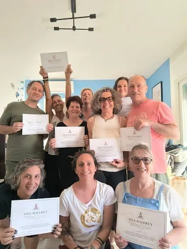 Un gruppo di allievi sorridenti mostra i propri certificati di yoga