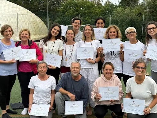 Un gruppo di allievi all'aperto, fra gli alberi, con i certificati in mano