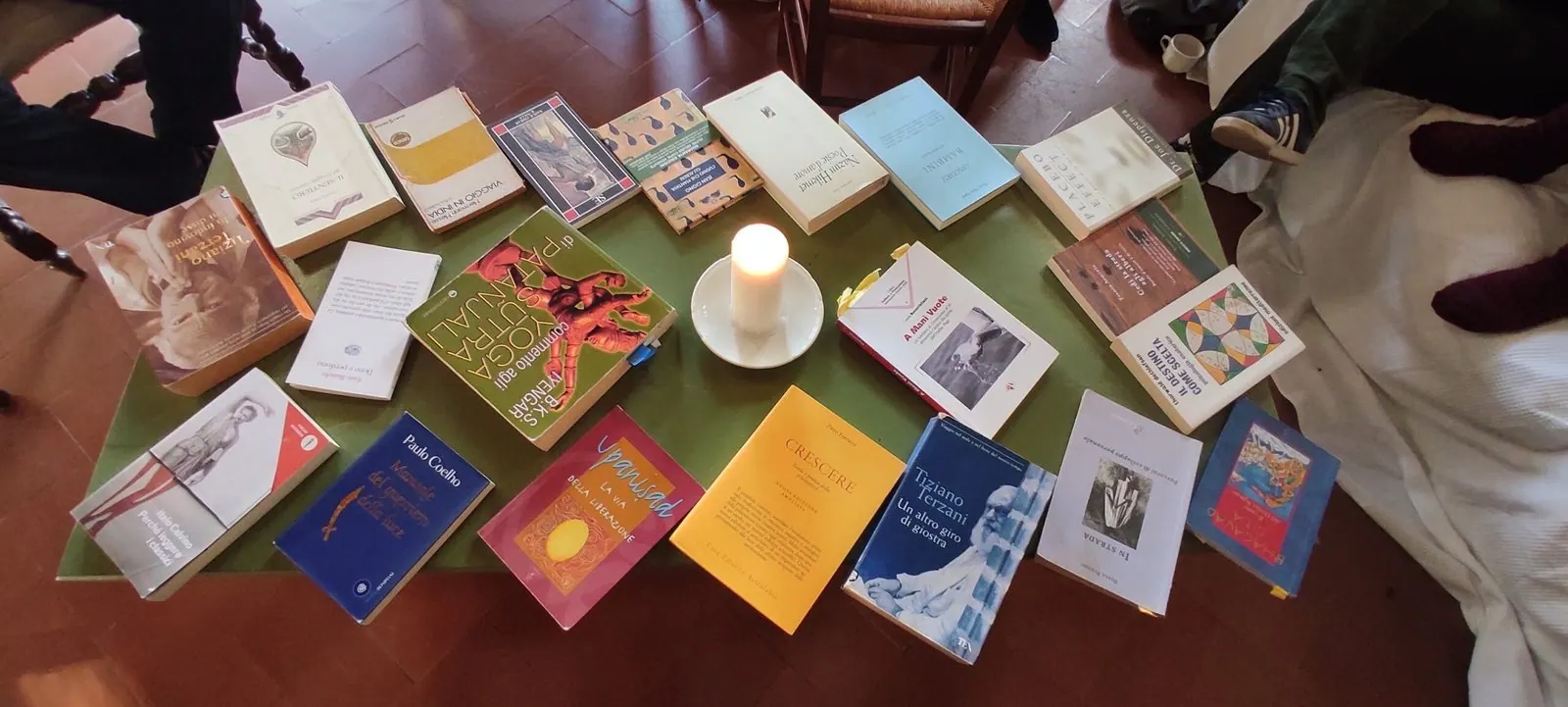 Libri e carte disposti sul tappeto attorno a una candela accesa