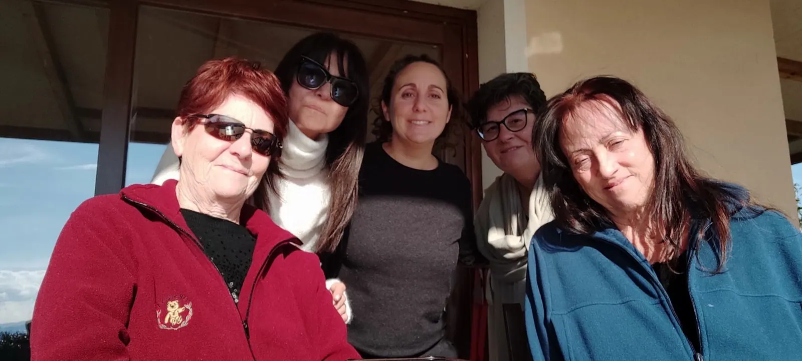 Cinque amiche sorridenti sulla veranda, al sole