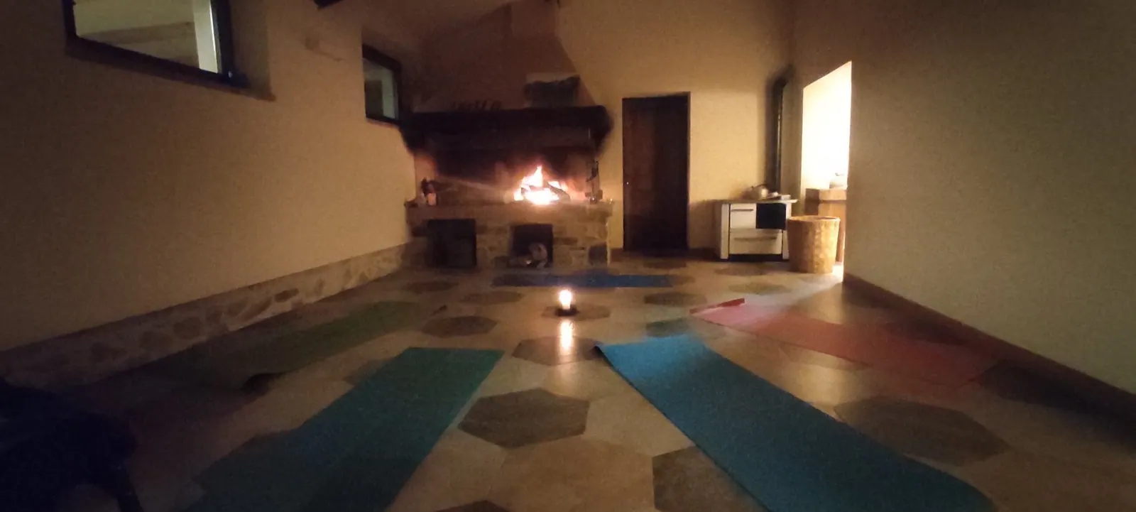 La sala della pratica a lume di candela, con i tappetini davanti al camino acceso