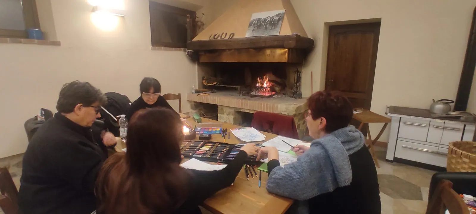 Le partecipanti attorno al tavolo vicino al camino, durante un laboratorio creativo