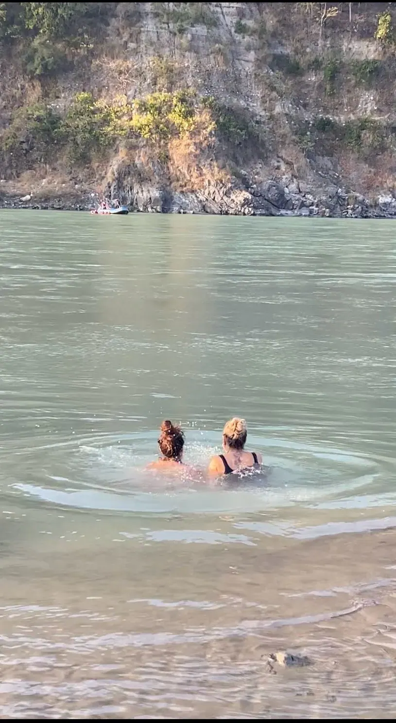 Due donne fanno il bagno nel fiume, immerse fino alle spalle nell'acqua verde e calma