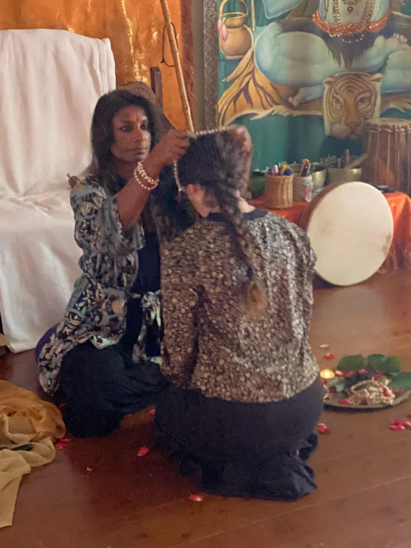 Un momento rituale della formazione con Nadeshwari Joythimayananda: una donna in ginocchio riceve una benedizione, accanto a un tamburo