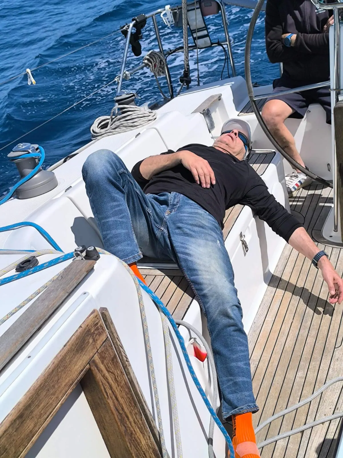 Un uomo sdraiato a riposare sul ponte della barca in navigazione