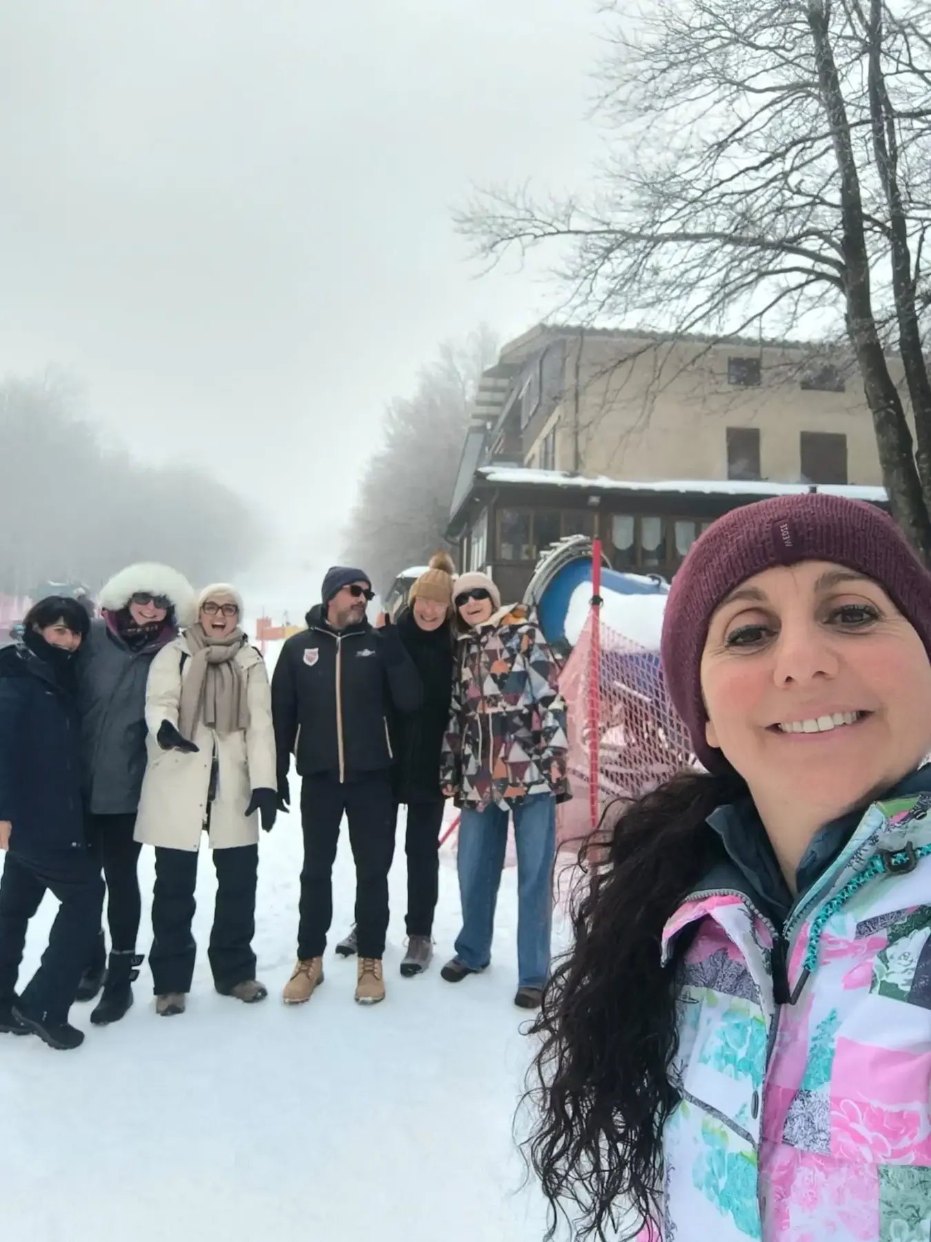 Selfie del gruppo sulla neve, con gli alberi spogli nella nebbia