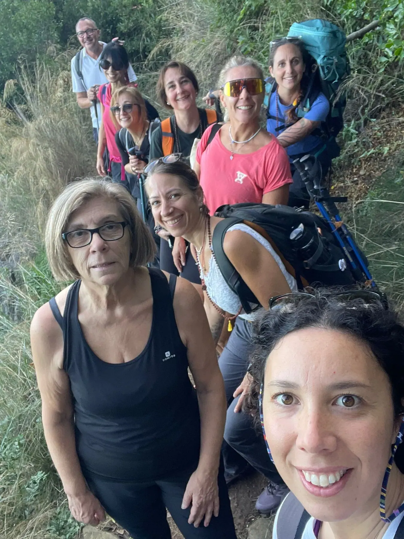 Selfie del gruppo sorridente lungo un sentiero fra la vegetazione