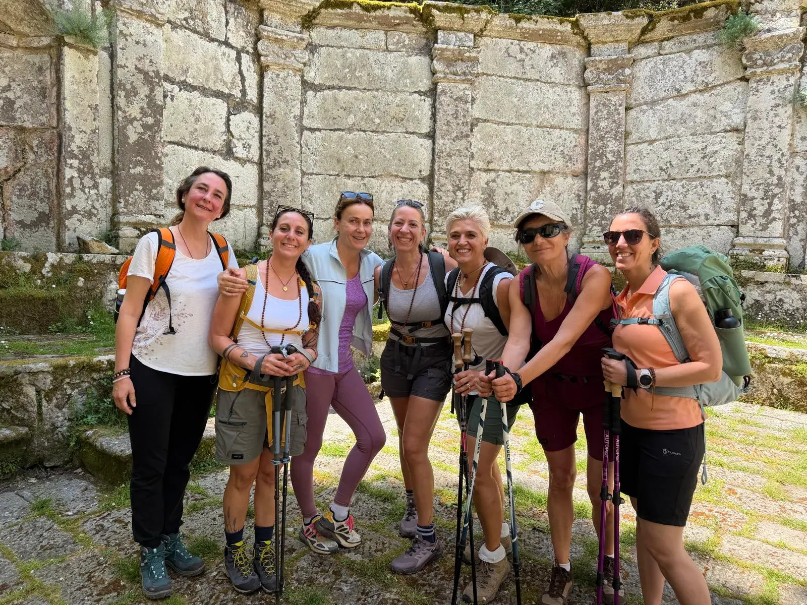 Il gruppo con zaini e bastoncini davanti a un antico muro di pietra