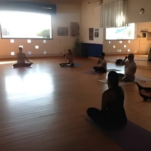 Allievi seduti in meditazione su un grande parquet, nella luce della sera
